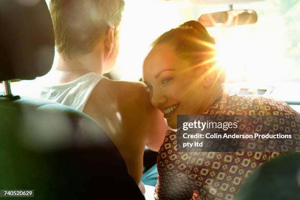 smiling woman leaning head on shoulder of man driving sunny car - couple in car smiling stockfoto's en -beelden