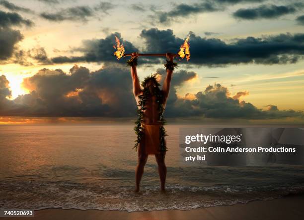 hawaiian man holding torches on beach - traditional hawaiian clothing photos et images de collection