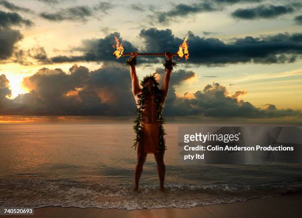 hawaiian man holding torches on beach - men in loincloths stock pictures, royalty-free photos & images