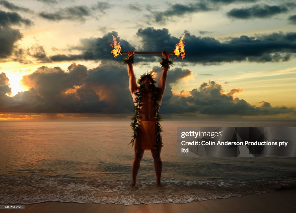 Hawaiian man holding torches on beach