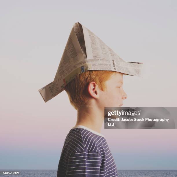 caucasian boy wearing paper hat near ocean - pirate hat stock pictures, royalty-free photos & images