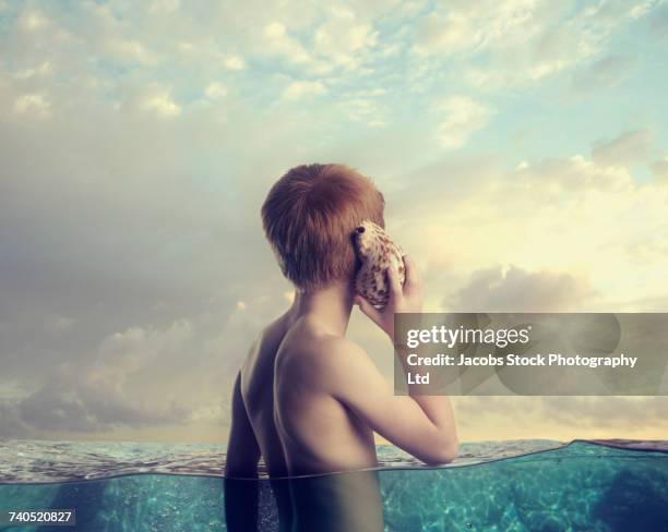 caucasian boy in ocean listening to seashell - 12 ears stock pictures, royalty-free photos & images