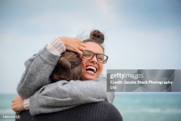 caucasian couple hugging on beach - water glasses ストックフォトと画像