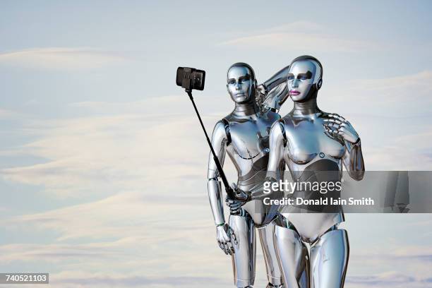 robot couple posing for cell phone selfie - selfiestick stock-fotos und bilder