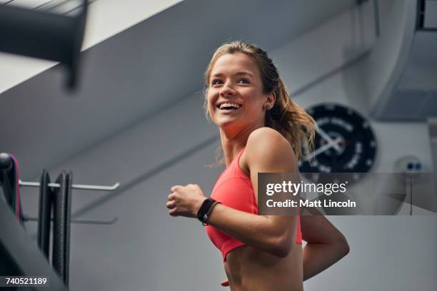 young woman training, running on gym treadmill looking over her shoulder - mirar por encima del hombro fotografías e imágenes de stock