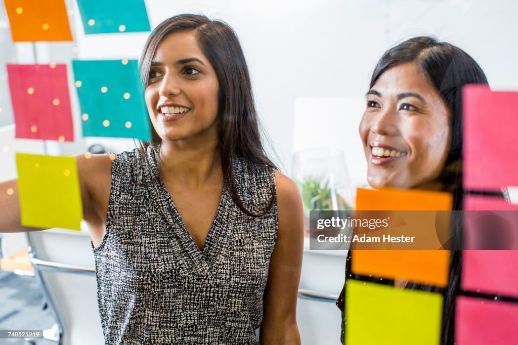 Women reading adhesive notes in office