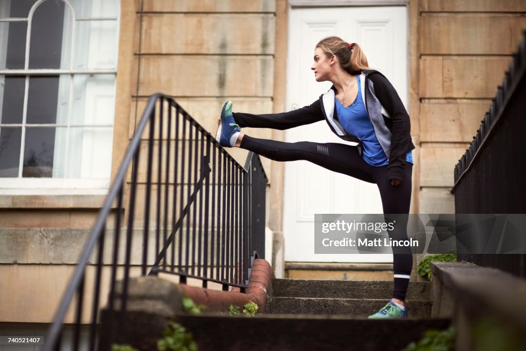 Young female runner outside front door touching toes
