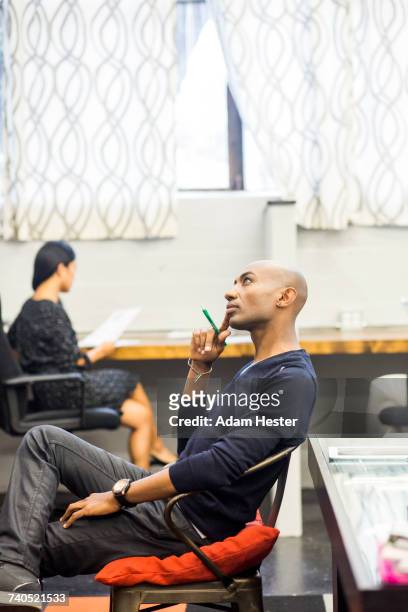 portrait of pensive african american man sitting in office - androgynous professional stock pictures, royalty-free photos & images