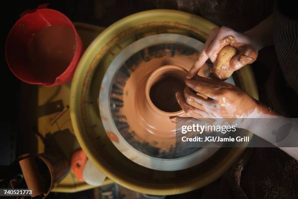 hands of caucasian woman shaping pottery clay on wheel - amoldar fotografías e imágenes de stock