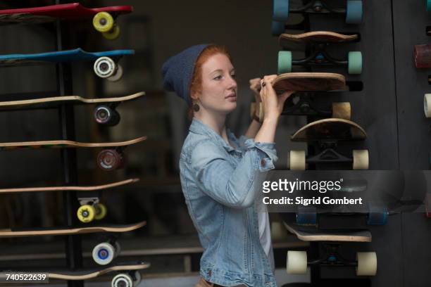 Woman working in skateboard shop, organising skateboard display