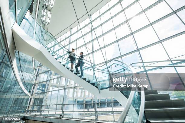 distant mixed race business people standing on staircase and talking - architecture low angle stock-fotos und bilder