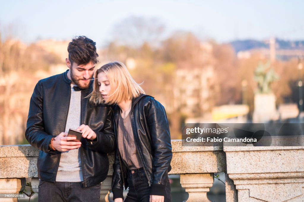 Caucasian couple texting on cell phone outdoors