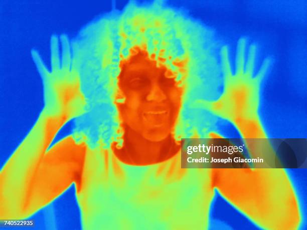 thermal image portrait of mid adult woman with raised hands - thermal imaging imagens e fotografias de stock