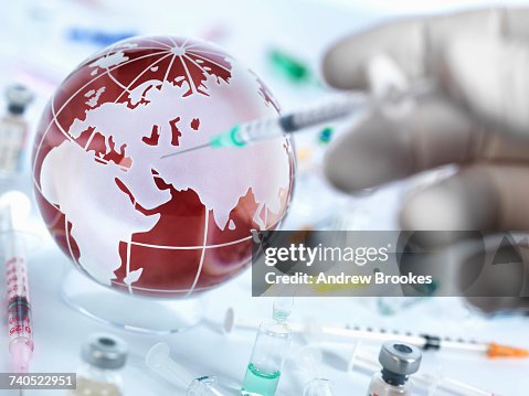 Doctor injecting globe with vaccine to illustrate a cure for a global pandemic Doctor injecting globe with vaccine to illustrate a cure for a global pandemic