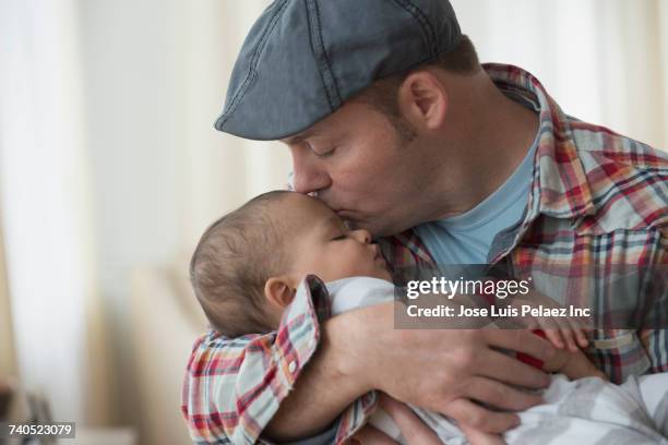 father kissing baby son on forehead - man sleeping with cap stock pictures, royalty-free photos & images