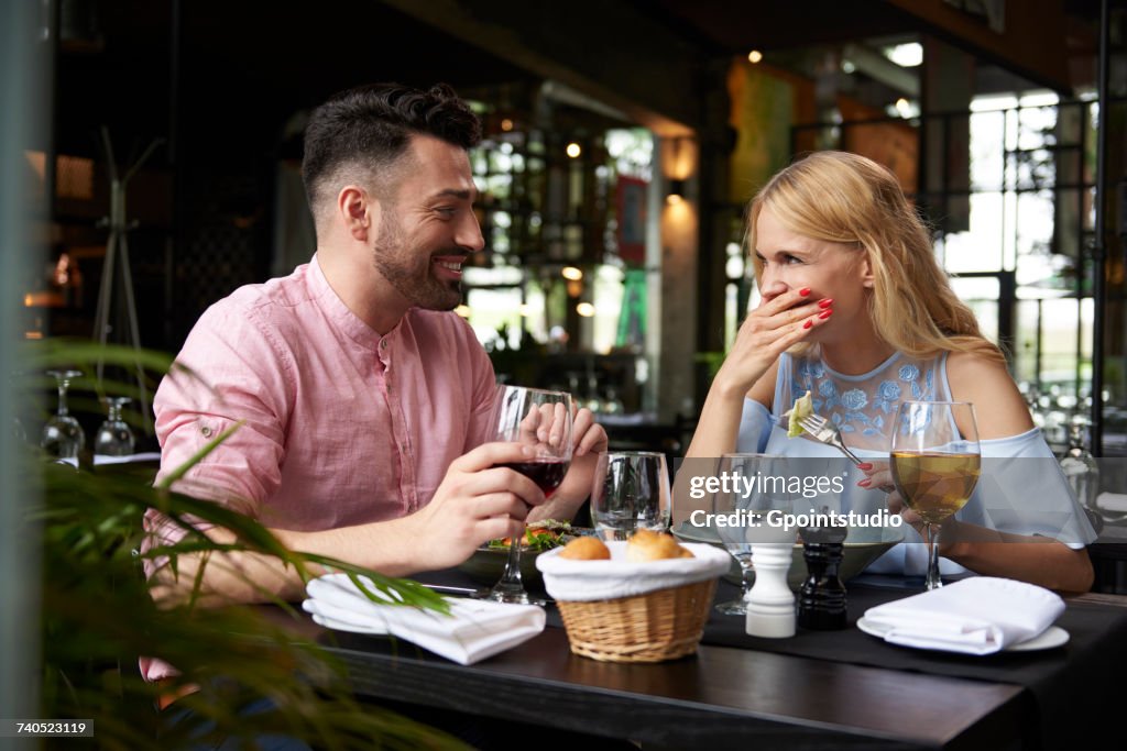 Young woman with boyfriend laughing at restaurant table