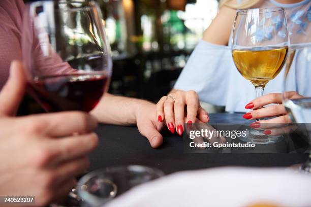 cropped view of womans hand on boyfriends hand at restaurant table - wine glass finger food stock-fotos und bilder