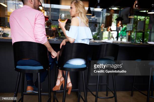 rear view of man touching angry young womans knee at bar - man touching womans leg stock pictures, royalty-free photos & images