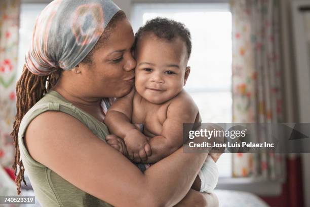 black mother kissing baby son on cheek - cheek stock pictures, royalty-free photos & images
