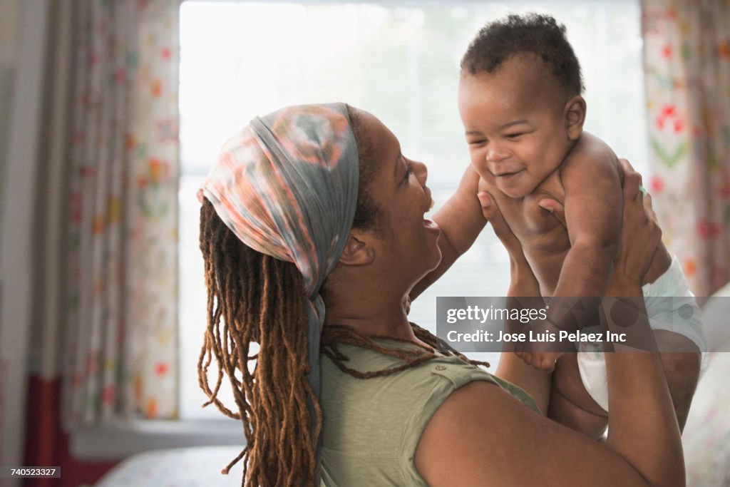 Black mother lifting baby son