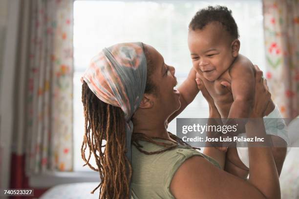black mother lifting baby son - black mom photos et images de collection