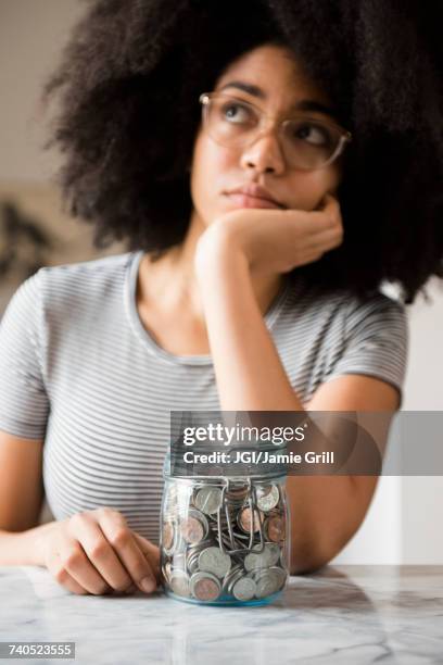 pensive african american woman with jar full of coins - full responsibility stock pictures, royalty-free photos & images