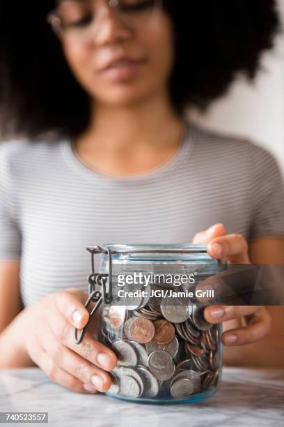 smiling african american woman with jar full of coins - money jar stock-fotos und bilder