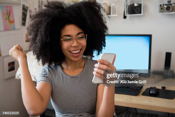 african american woman texting on cell phone and celebrating - goda nyheter bildbanksfoton och bilder