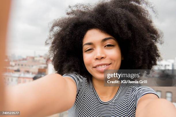 smiling african american woman posing for selfie on rooftop - african cityscape stock-fotos und bilder