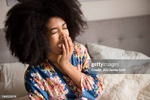 african american woman sitting in bed and yawning - un giorno nella vita foto e immagini stock