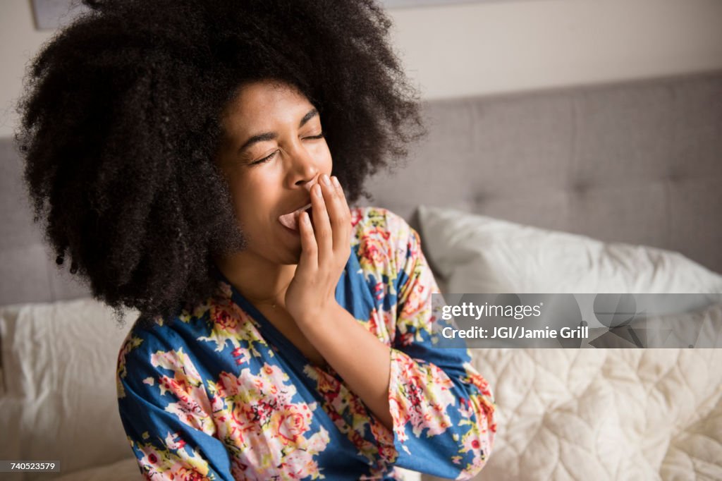 African American woman sitting in bed and yawning