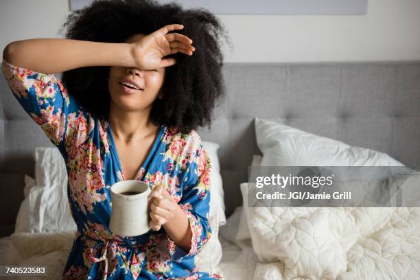 african american woman sitting in bed drinking coffee - this morning 2017 ストックフォトと画像