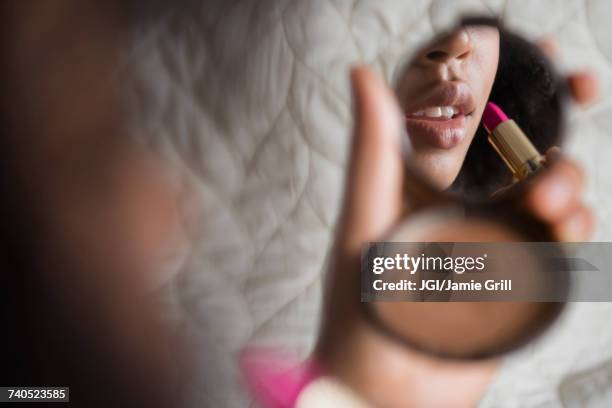 african american woman using compact applying lipstick - compact foto e immagini stock