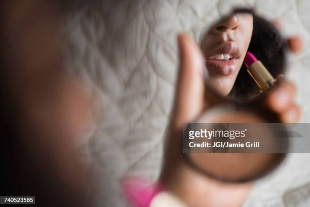 african american woman using compact applying lipstick - applying lipstick ストックフォトと画像