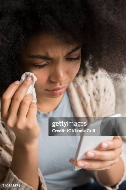 african american woman crying and texting on cell phone - handkerchiefs people stock pictures, royalty-free photos & images