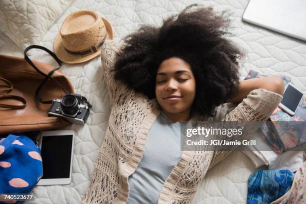 african american woman laying on bed anticipating travel - vacation planning stock pictures, royalty-free photos & images