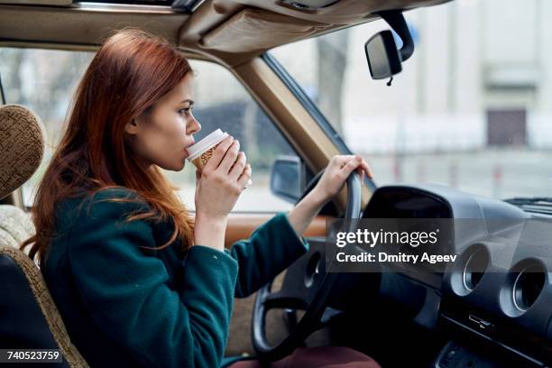 caucasian woman driving car and drinking coffee - one person in focus stock pictures, royalty-free photos & images