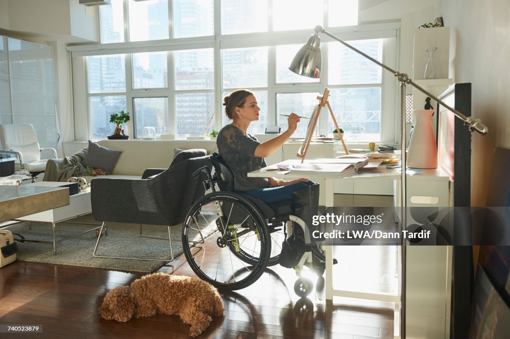 Caucasian woman in wheelchair painting on easel