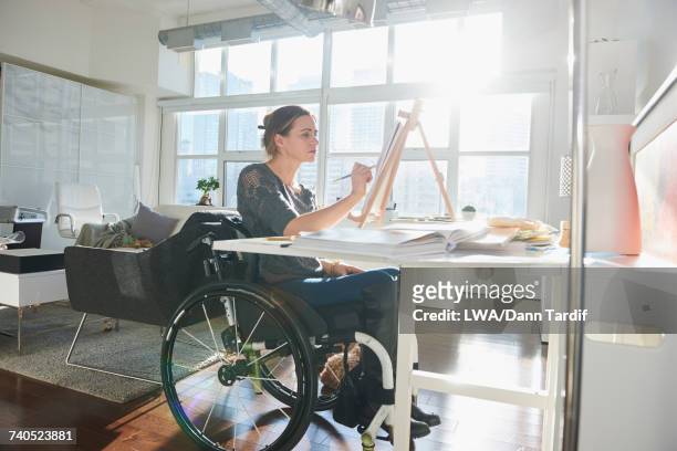 caucasian woman in wheelchair painting on easel - artists with animals stock pictures, royalty-free photos & images