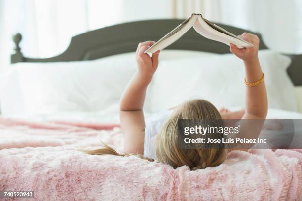 caucasian girl laying on bed reading book - american literature stock pictures, royalty-free photos & images