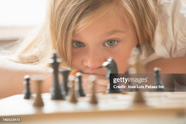 caucasian girl examining chess game board - chess game stockfoto's en -beelden