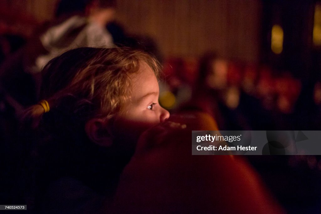 Caucasian girl leaning on chair watching movie in theater