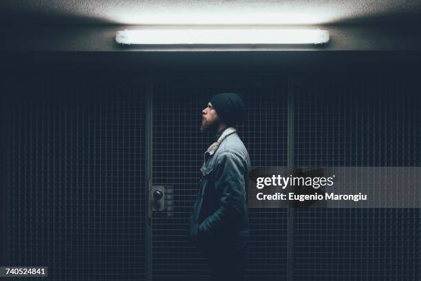 young male hipster in dark city doorway at night - fluorescent stock-fotos und bilder