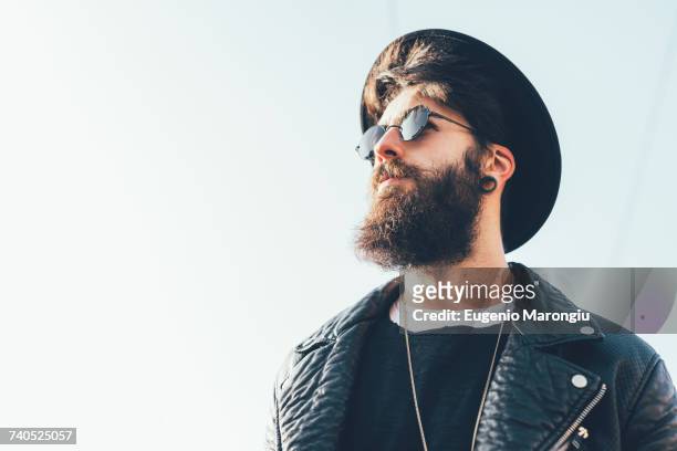 young male hipster wearing sunglasses and trilby looking up - bearded man stock-fotos und bilder