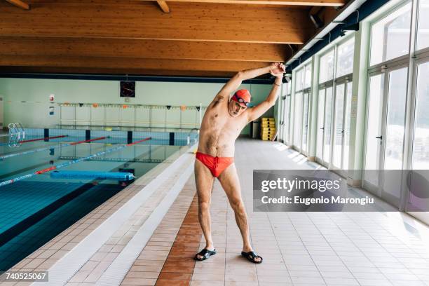 senior man stretching by swimming pool - badehose stock-fotos und bilder