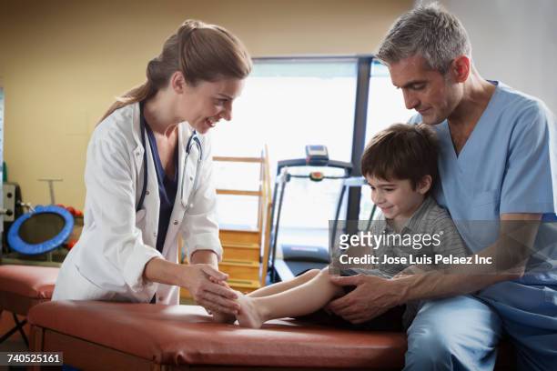 doctor and nurse examining legs of boy - table leg stock pictures, royalty-free photos & images