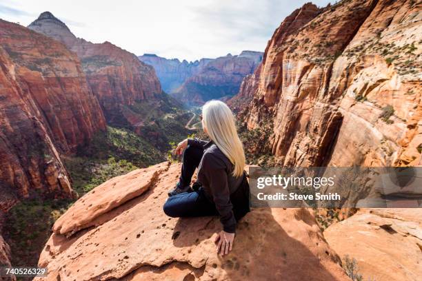 Caucasian woman sitting on rock admiring scenic view of rock formations