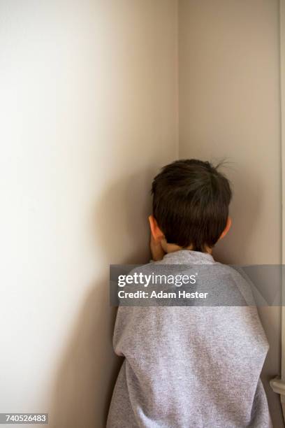 mixed race boy standing in corner - punishment stock pictures, royalty-free photos & images