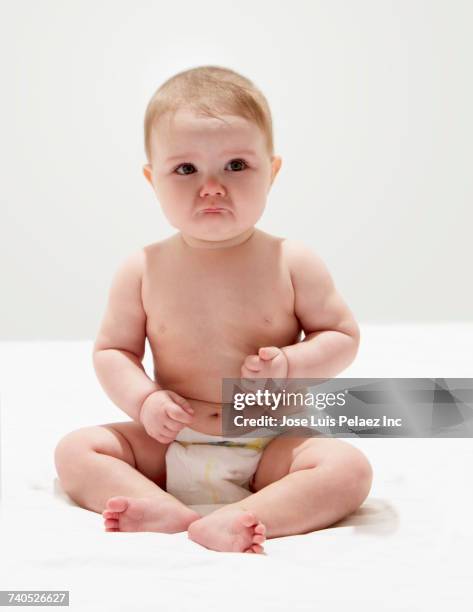 portrait of crying baby girl wearing diaper sitting on floor - sólo bebés fotografías e imágenes de stock