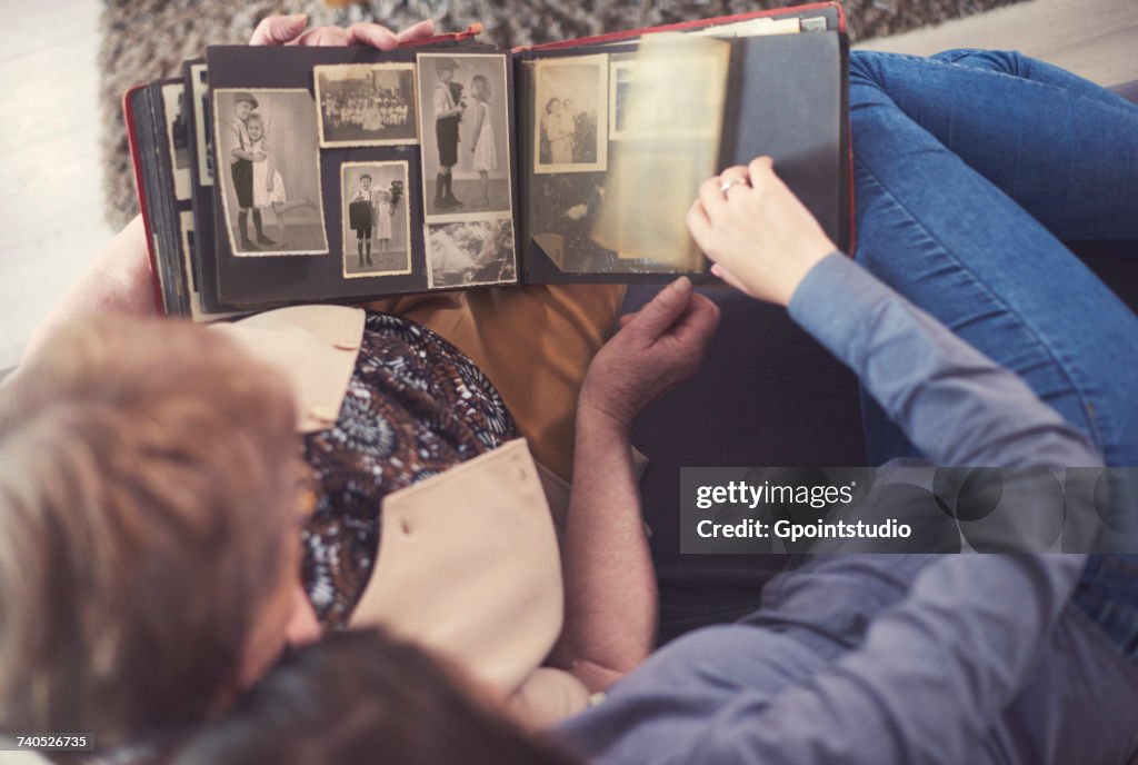 Overhead view of young woman on sofa with grandmother looking at photo album